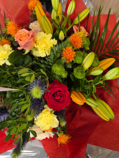 Fire & Gold - A fiery bouquet bursting with rich reds, vibrant oranges and golden yellows, balanced with fresh greens for a bold, energetic finish.