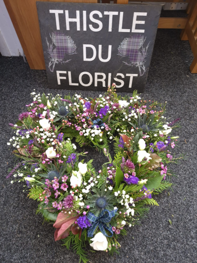 Highland Memories Wreath - A natural open wreath in purple and white, finished with traditional tartan ribbon.